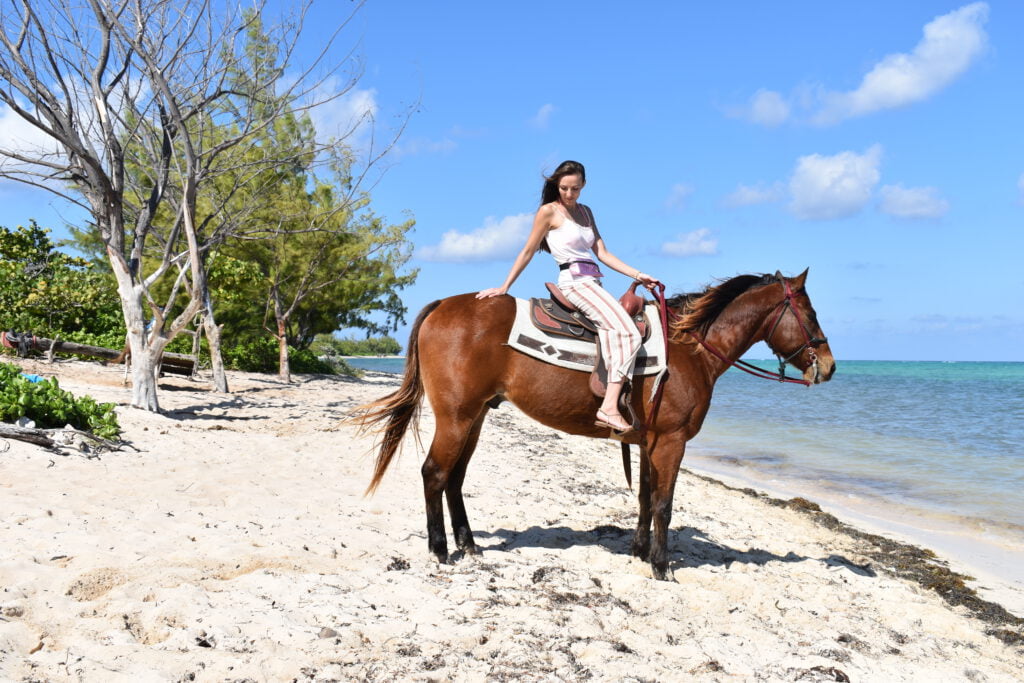 Mathilde fra World On Horseback på en hest, på en strand i Cayman Islands. 